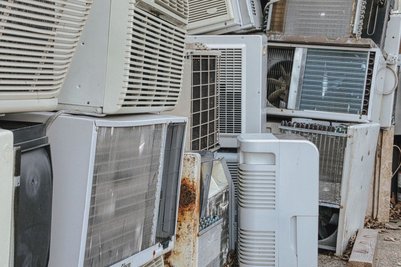 services-03 A collection of various old and broken air conditioning units piled outdoors.