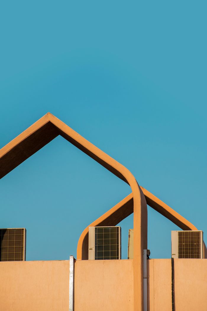 gallery-5 Modern architectural design featuring geometric roof structure and air conditioning units against a clear blue sky.