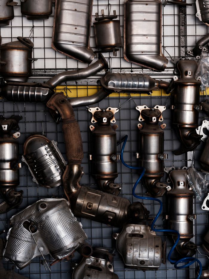 about-img Collection of vintage car exhaust parts hanging in an industrial workshop setting.